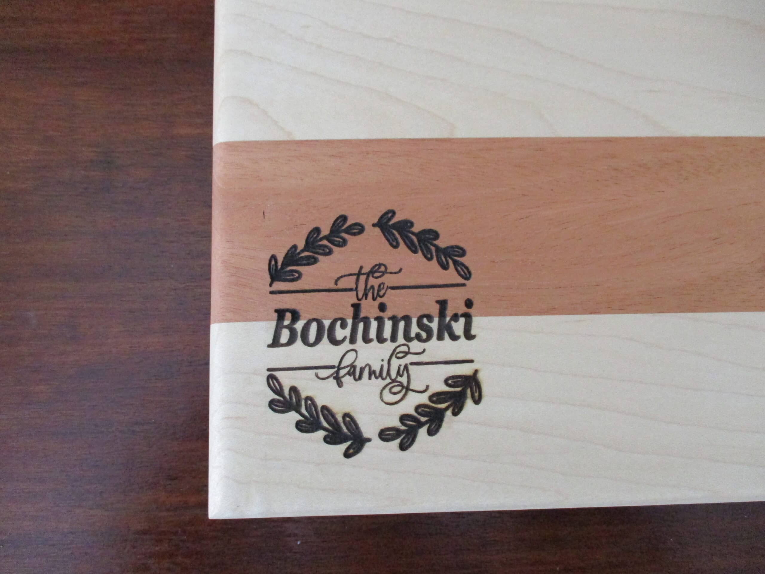 Custom wreath with family name engraved on Maple and Cherry cutting board/charcuterie board as a corporate gift.