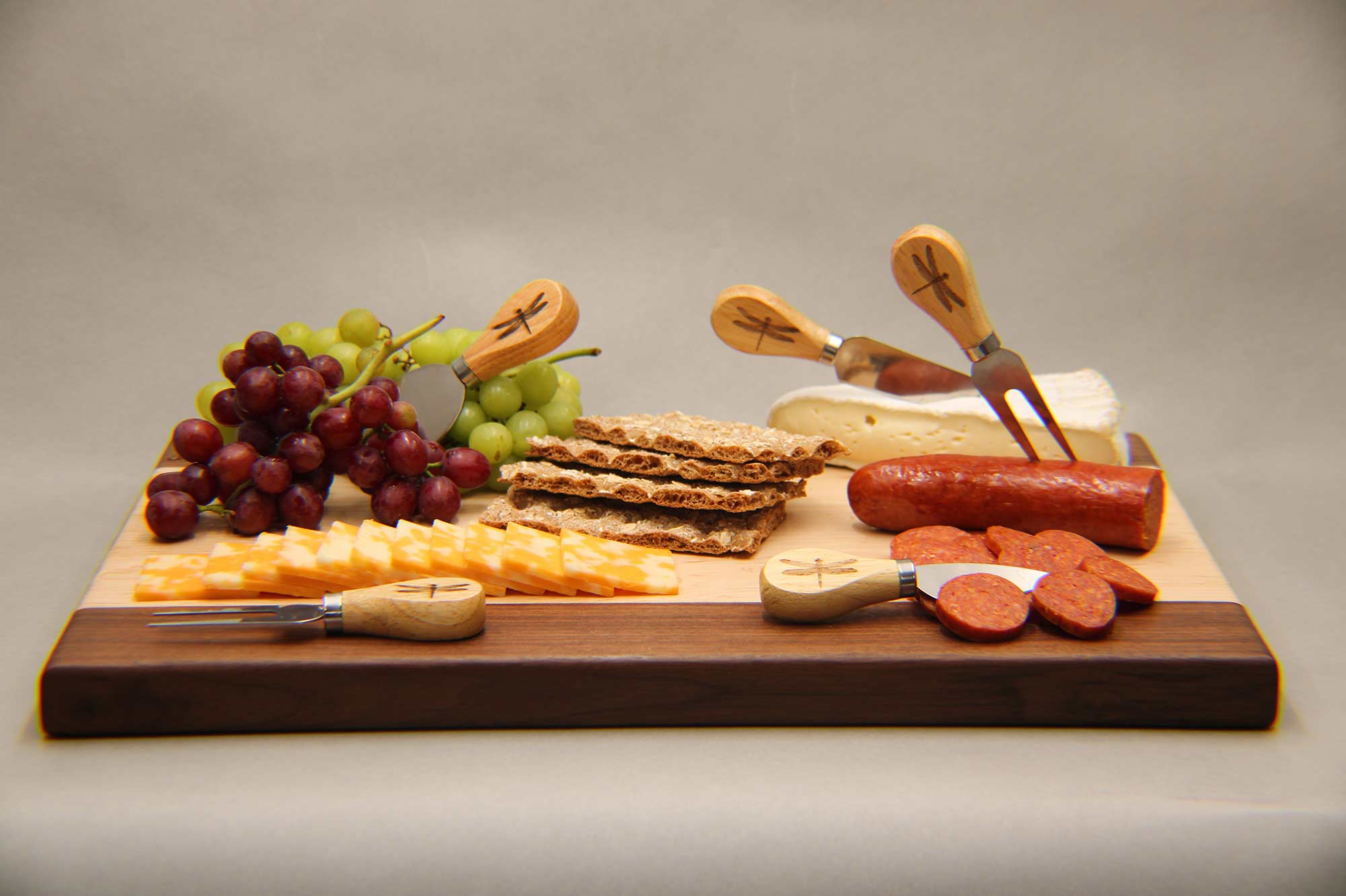 custom charcuterie board featuring cutlery, cheese and grapes