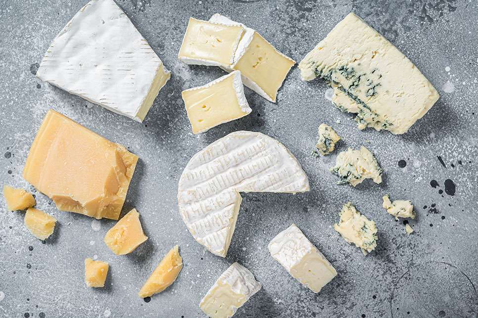 Assortment of cheese. Camembert, brie, blue cheese, parmesan. Gray background. Top view.