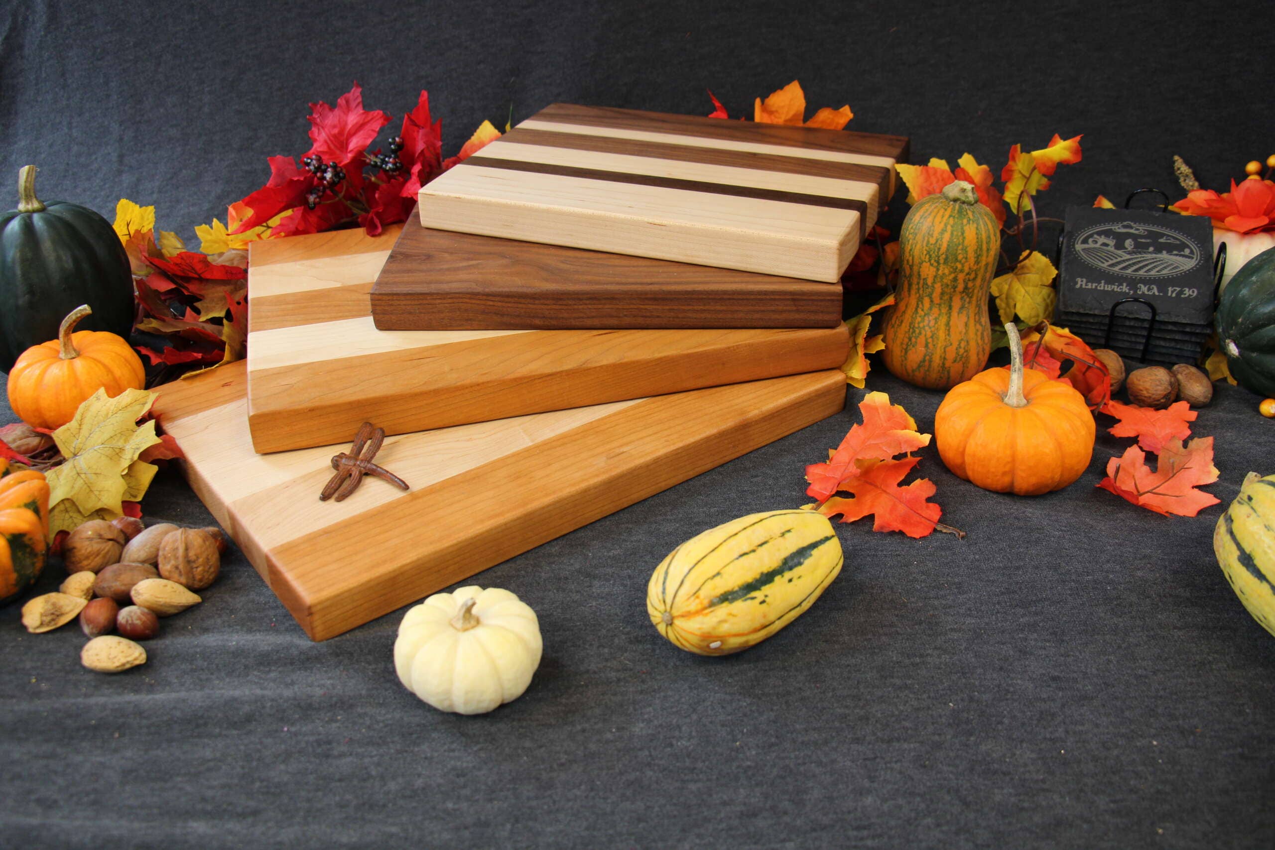 4 Wood Cutting and Charcuterie Boards surrounded by a number of real and fake gourds and fall foliage