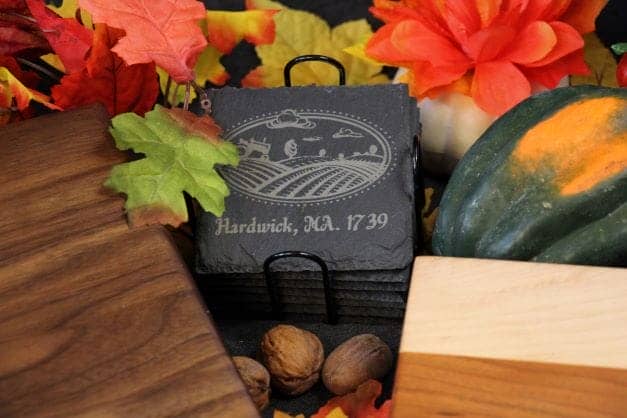 A set of eight customizable 4-inch square slate coasters with a wire rack. The coasters are made of natural slate and can be engraved with any design you choose. Perfect for protecting your furniture and adding a touch of personality to your home décor.