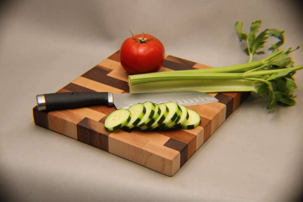 Knife and vegetables on a stunning mixed wood cutting board dragonfly wood arts